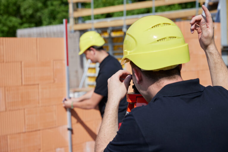 Bauprofis mit Schutzhelmen arbeiten an einer Mauer